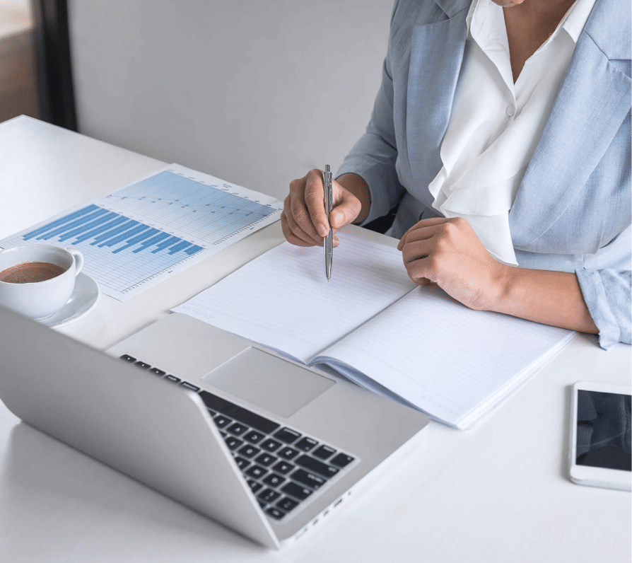Controle pré-audit : femme qui écrit avec un stylo sur un carnet devant un ordinateur